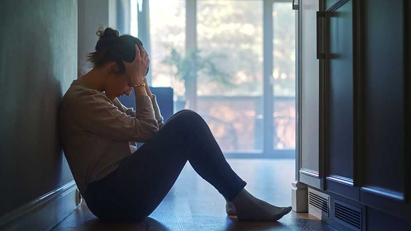 Young woman sitting on the floor and grieving the loss of a loved one