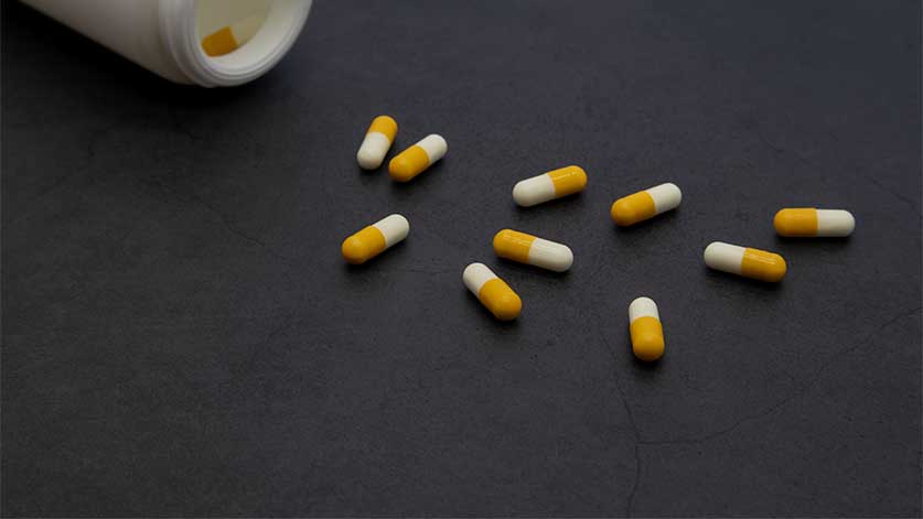 white and orange adderall pills scattered on a table top - Adderall Withdrawal Symptoms | Timeline, Detox, & Treatment